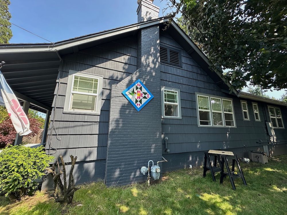The side of our house, showing a chimney with a hummingbird-themed barn quilt
