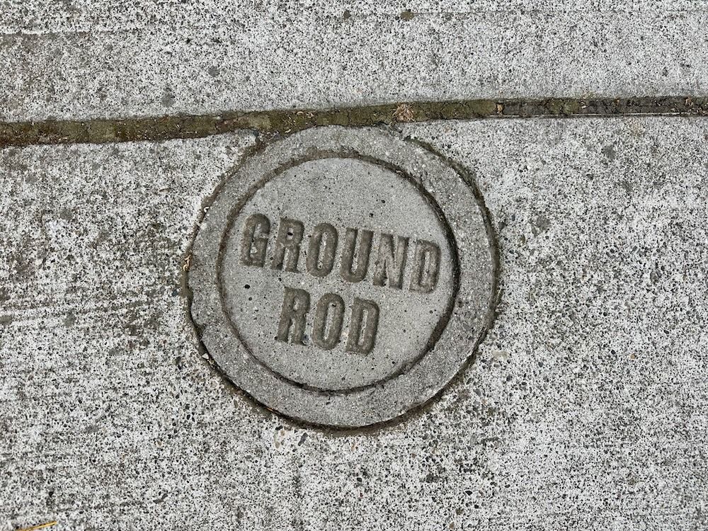 "A photo of a concrete cover that reads 'GROUND ROD'"